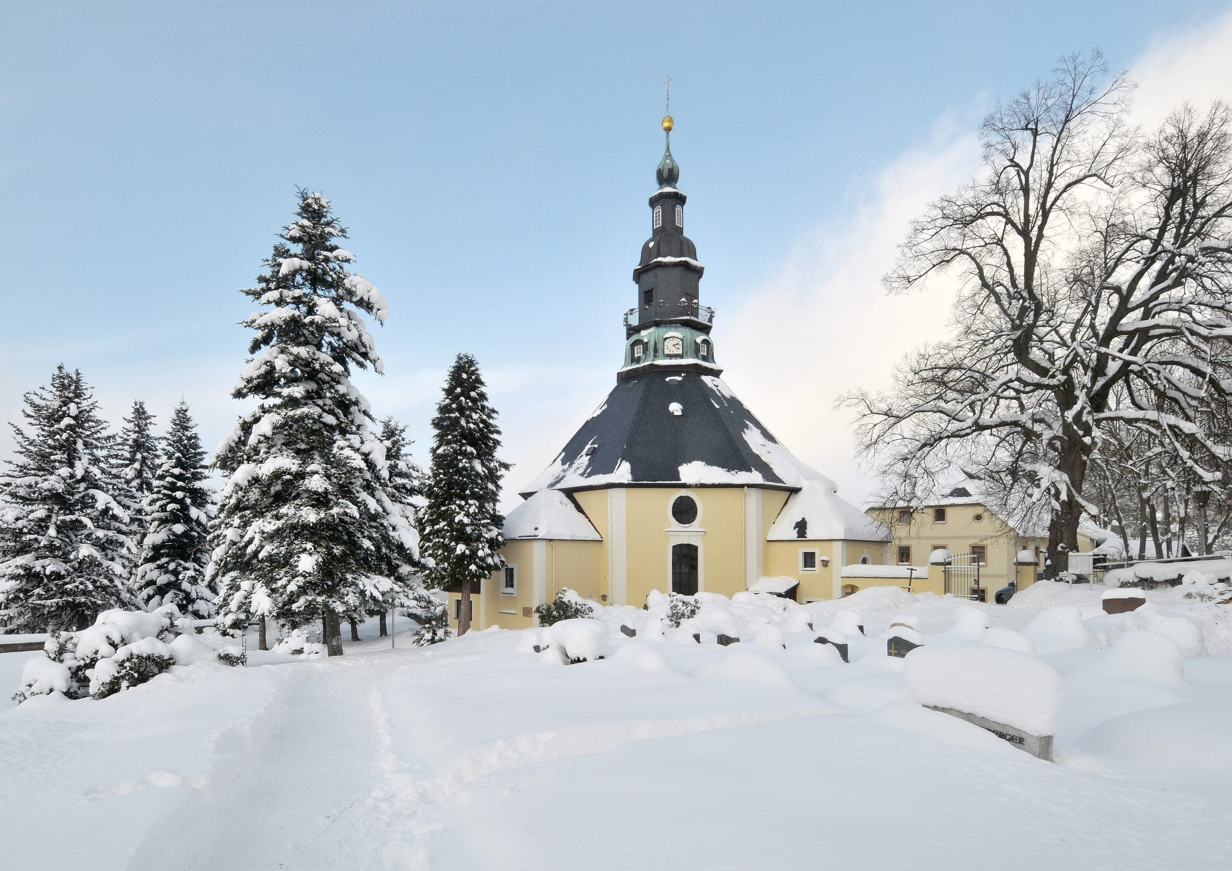 Snow-laden firs frame the octagonal Bergkirche in Seiffen on a bright December day.