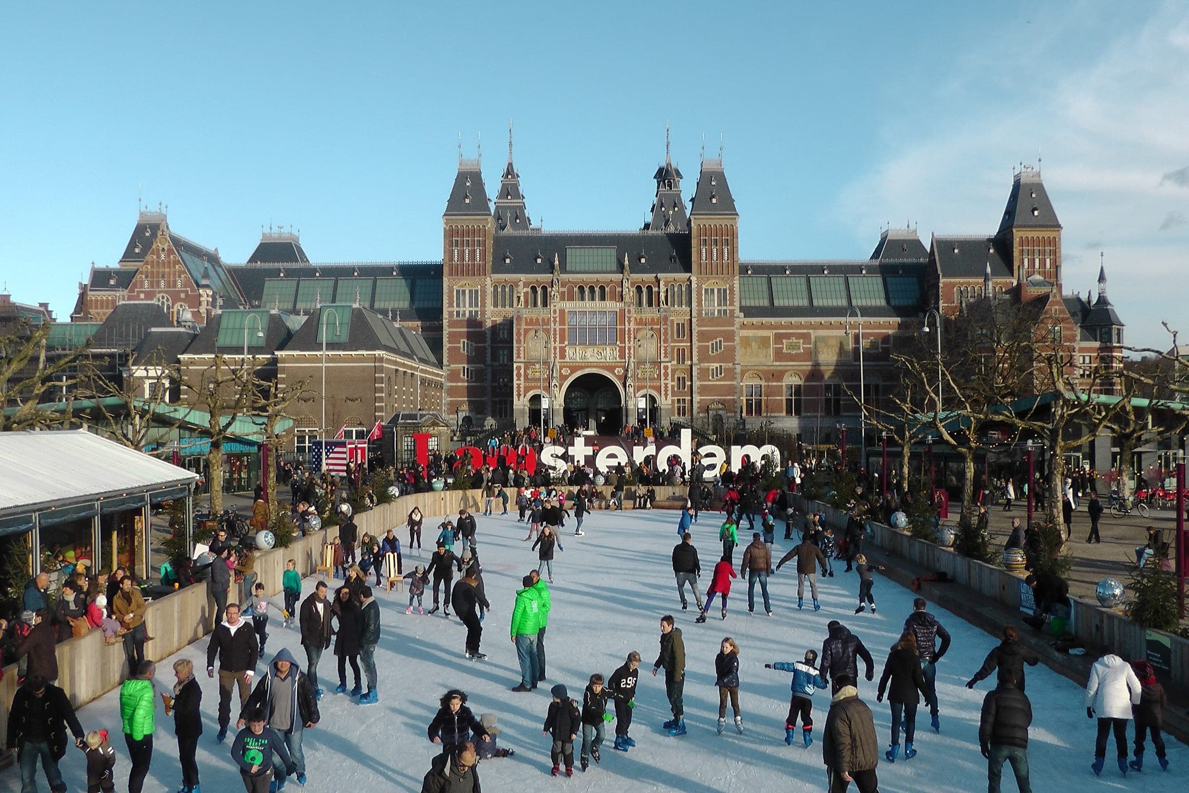 Skaters circle a winter ice rink on the Museumplein in Amsterdam in front of the Rijksmuseum.