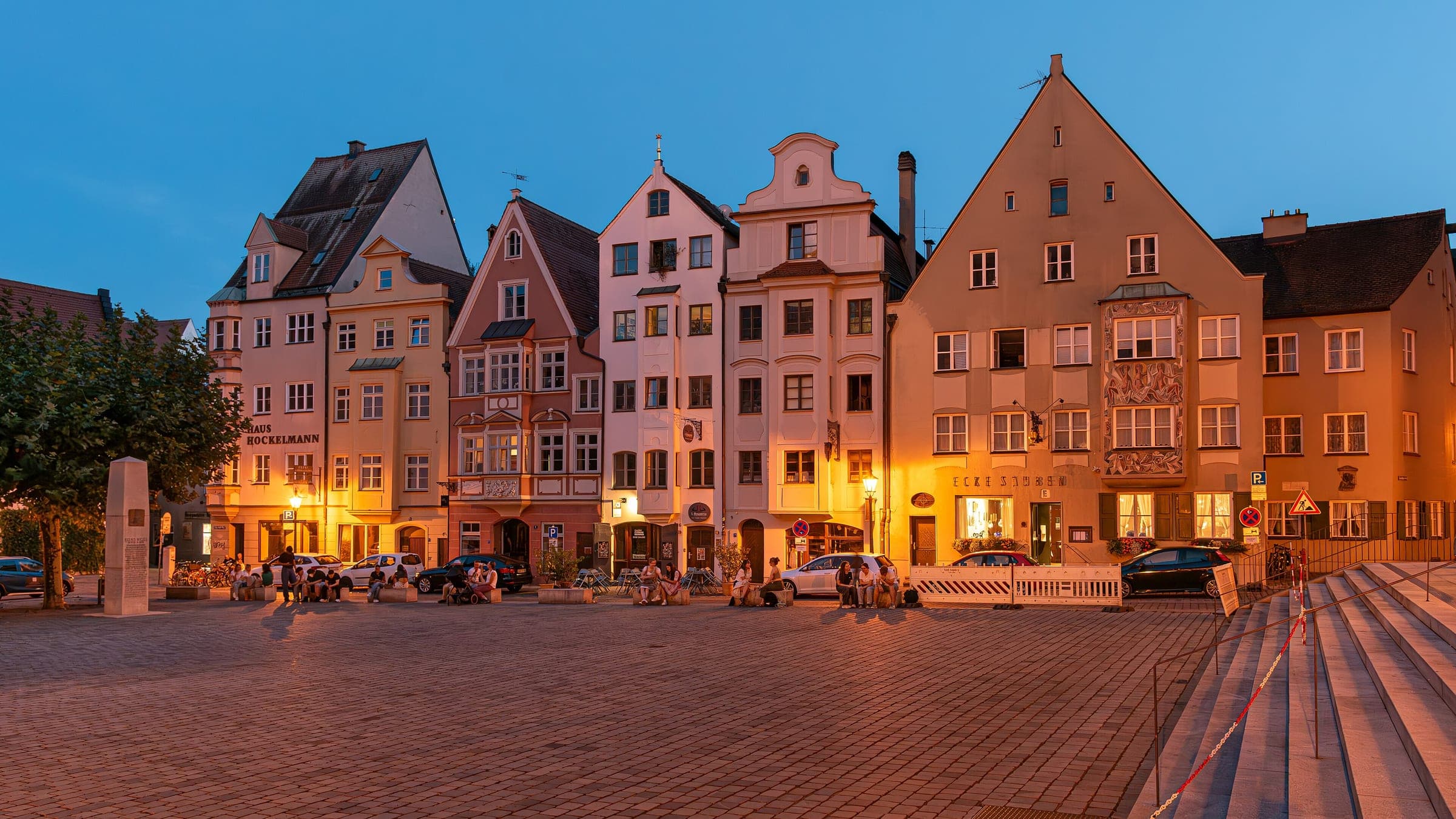 Gabled houses on Elias-Holl-Platz in Augsburg glow under the evening sky at dusk.