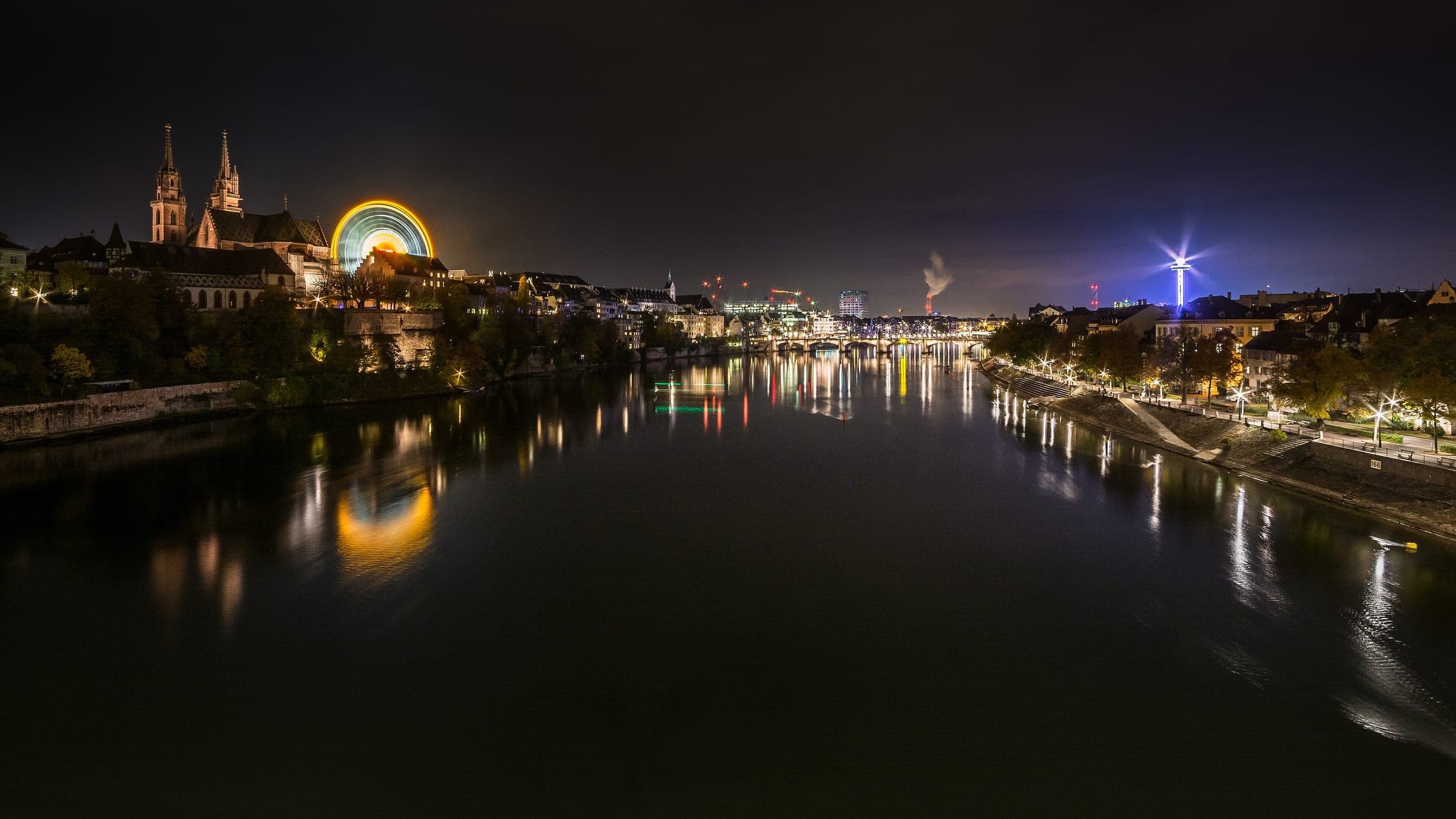 The lights of Basel reflect in the Rhine at night with the Minster towers on the left bank